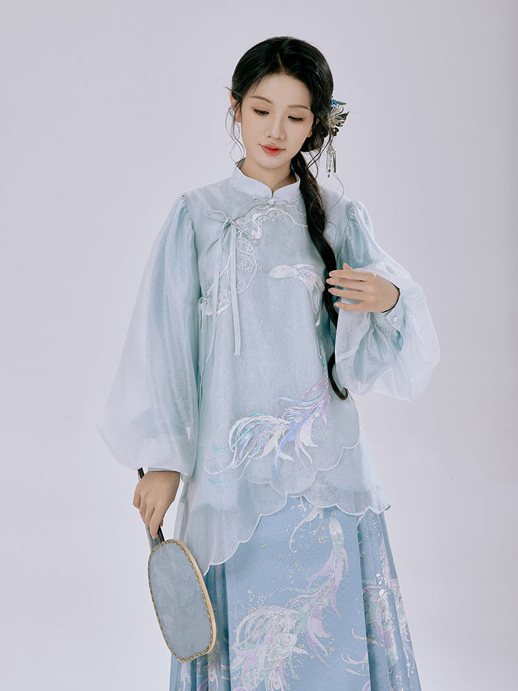 Model showcasing the modern hanfu Ethereal Koi Set with arms extended, revealing the elegant drape of the celadon blue fabric and intricate embroidery details.