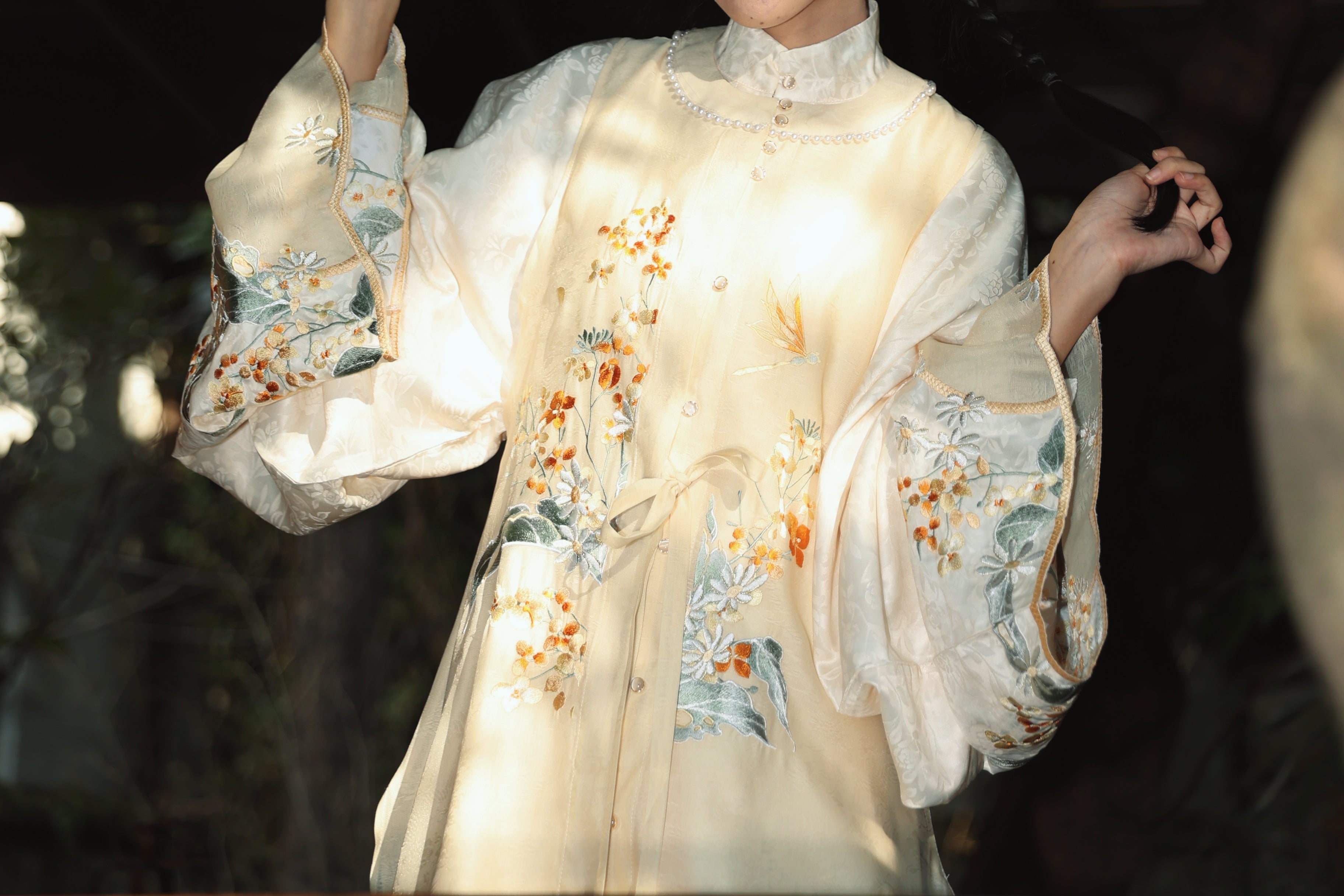 Close-up of cream-colored Mamian skirt showing detailed gold thread embroidery of playful bunnies and blue flower accents, featuring dimensional embroidery techniques perfect for modern hanfu enthusiasts