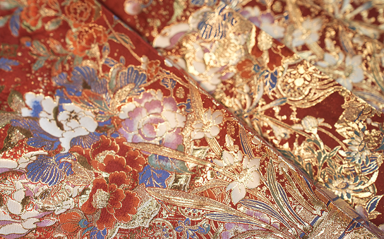 Close-up of HuaXia Ceremony Collection Hanfu dress fabric showing detailed embroidery of seasonal Chinese flowers including peony, lotus, and chrysanthemum with gold-thread outlines resembling traditional ink wash paintings